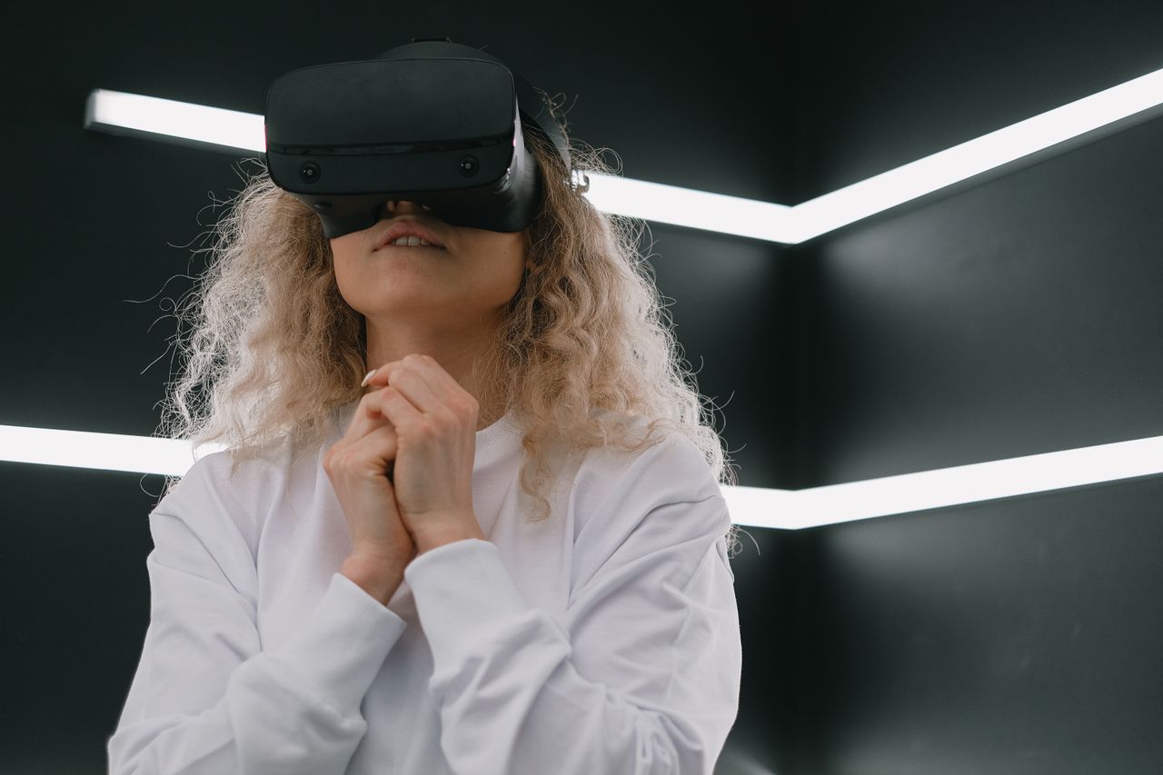 A woman in a white sweatshirt engaged with virtual reality indoors.